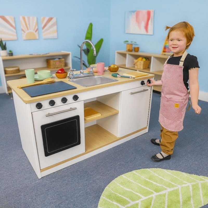 Children engaged in dramatic kitchen play with the Whitney Brothers elevatED Kitchen Island Breakfast Bar, showing the 360-degree design with the chef's kitchen front face and breakfast bar