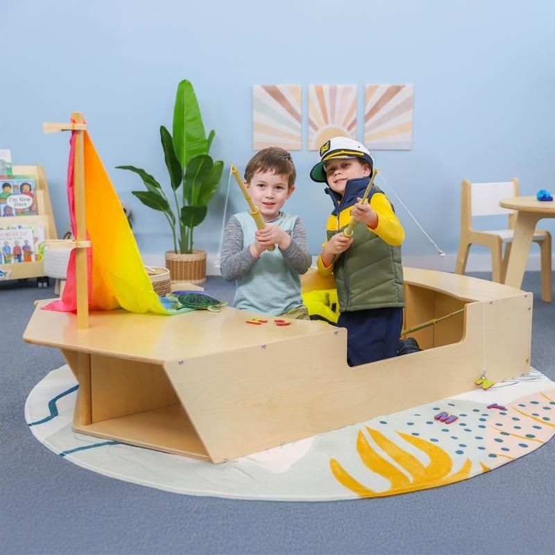 Two children playing on the Whitney Brothers Imagination Boat, showing the open deck design with space for up to four children and the crawl-through bow spaces of the classroom play boat