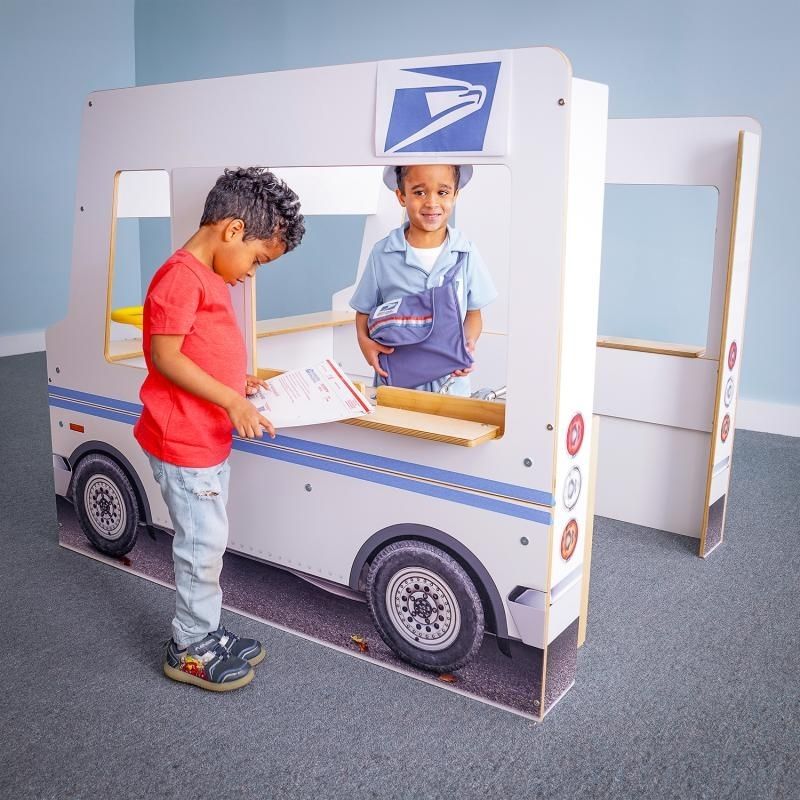 Child at the serving counter of the Whitney Brothers Imagination Truck, showing how the side-panel counters enable customer-and-server dramatic play scenarios at the classroom play vehicle
