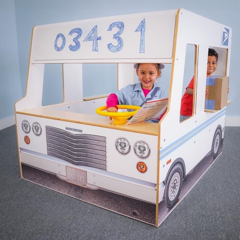 Front view of the Whitney Brothers Imagination Truck with two children in driver and passenger positions, showing the windshield dry erase board and realistic front grill exterior details