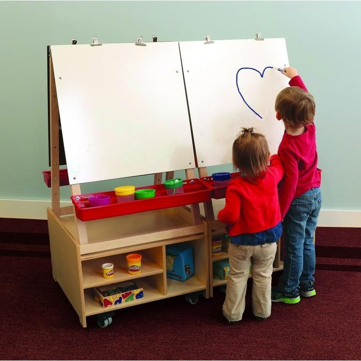 Two children using the Whitney Brothers Mobile Art Center Four Station Set, painting on the double-sided easels with adjustable paint trays and write-and-wipe panels in a classroom setting
