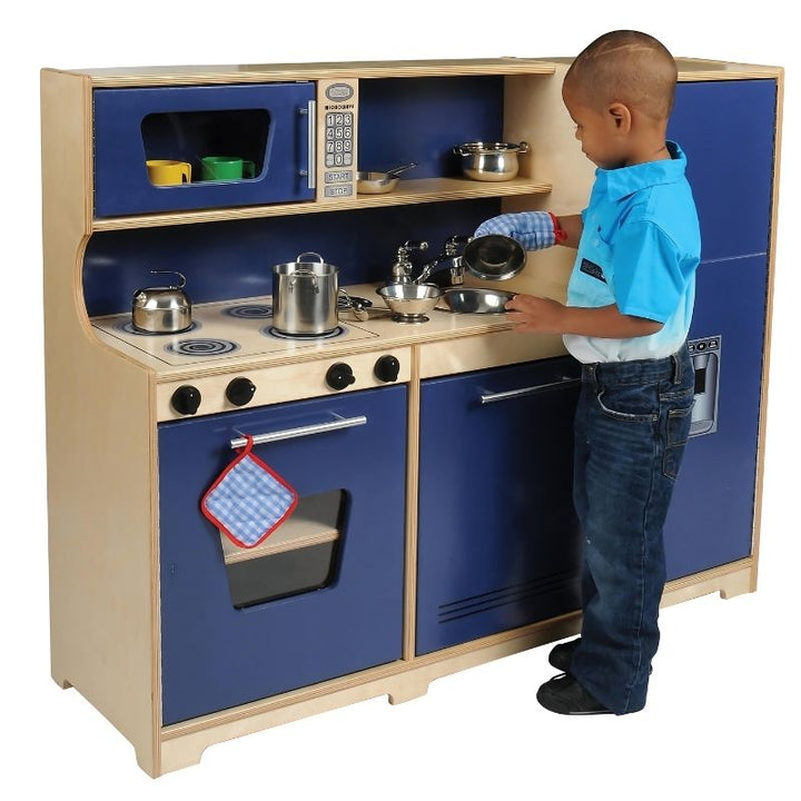 Child engaged in pretend cooking at the Whitney Brothers Monaco Combo Kitchen, showing the realistic stove dials and integrated all-in-one birch plywood play kitchen design