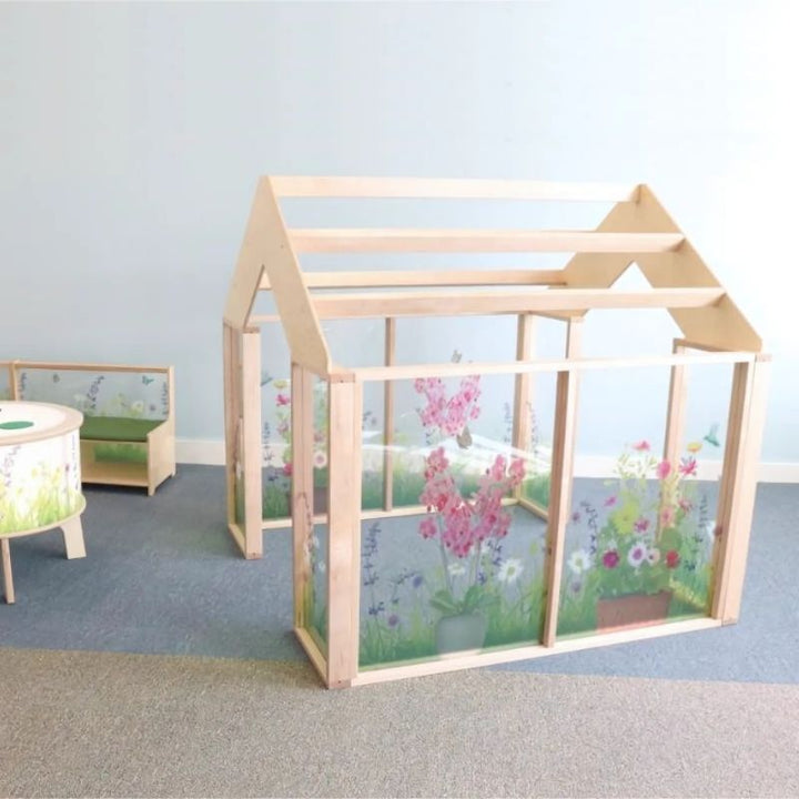 Side view of the Whitney Brothers Nature View Play Greenhouse showing the shatterproof acrylic panels printed with wildflower fields and the open pergola-style roof for air circulation and visibility