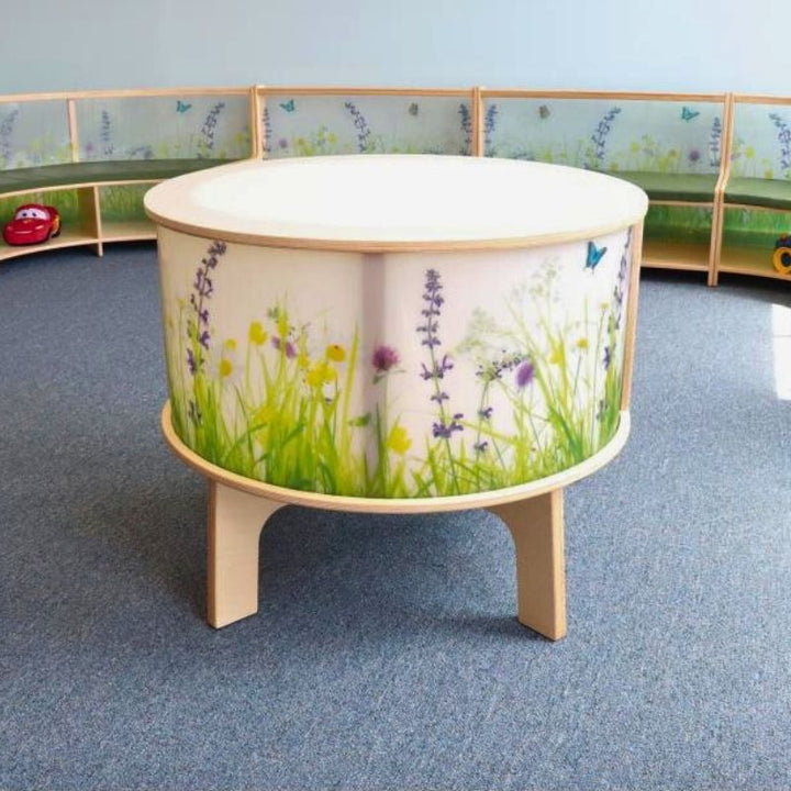Portrait view of the Whitney Brothers Nature View Radiant LED Light Table showing the full cylinder form with the illuminated Nature View side panels glowing and the birch plywood leg construction