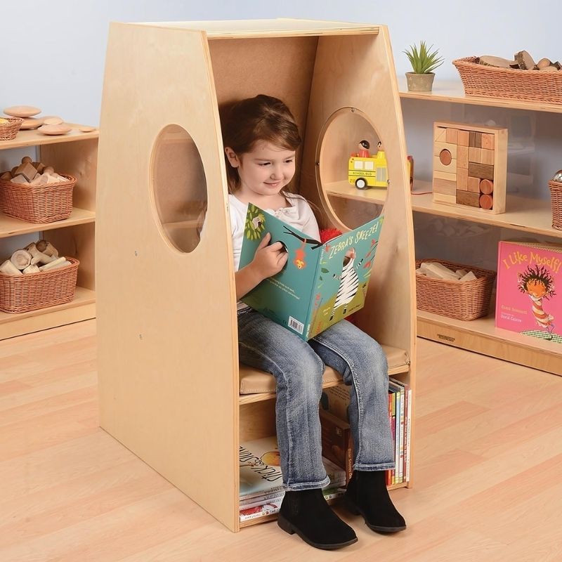 Child actively reading inside the Whitney Brothers Nestled Nook on the blue cushion, demonstrating the calm corner reading nook in use in a classroom or home environment