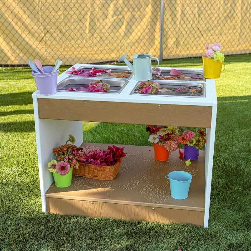 Whitney Brothers outdoorED outdoor sensory table front view styled with flowers in an outdoor classroom setting, showing textured woodgrain maple and polar white HDPE finish