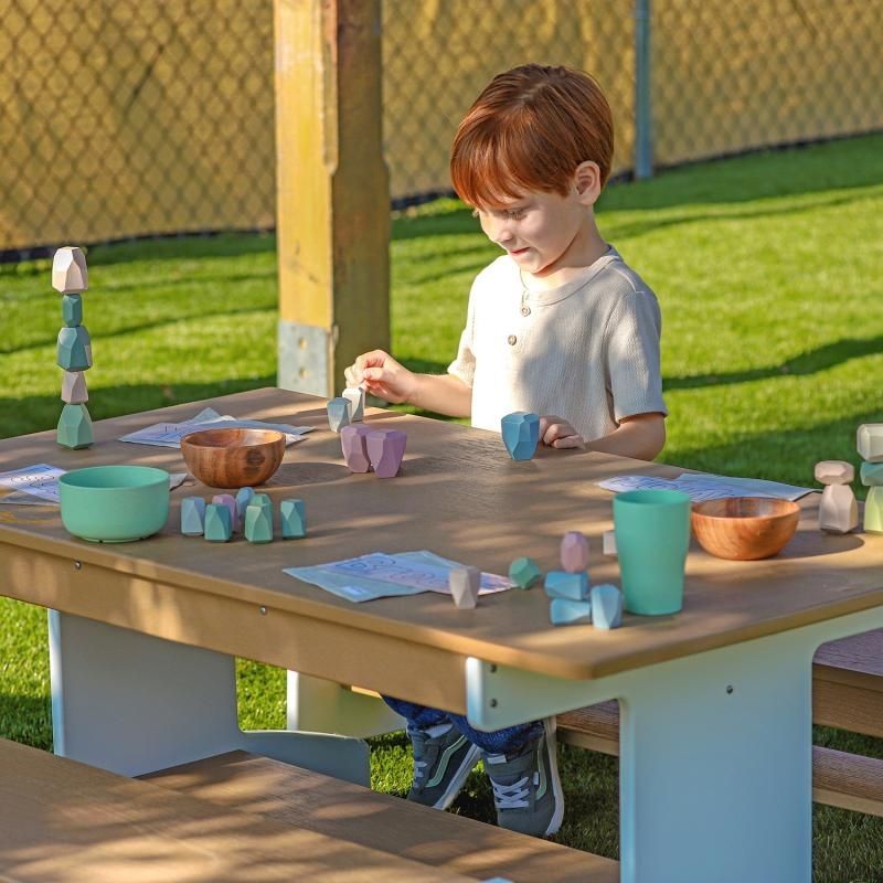 Child playing independently at Whitney Brothers outdoorED outdoor classroom table, showing ergonomic seating height for preschool-aged learners