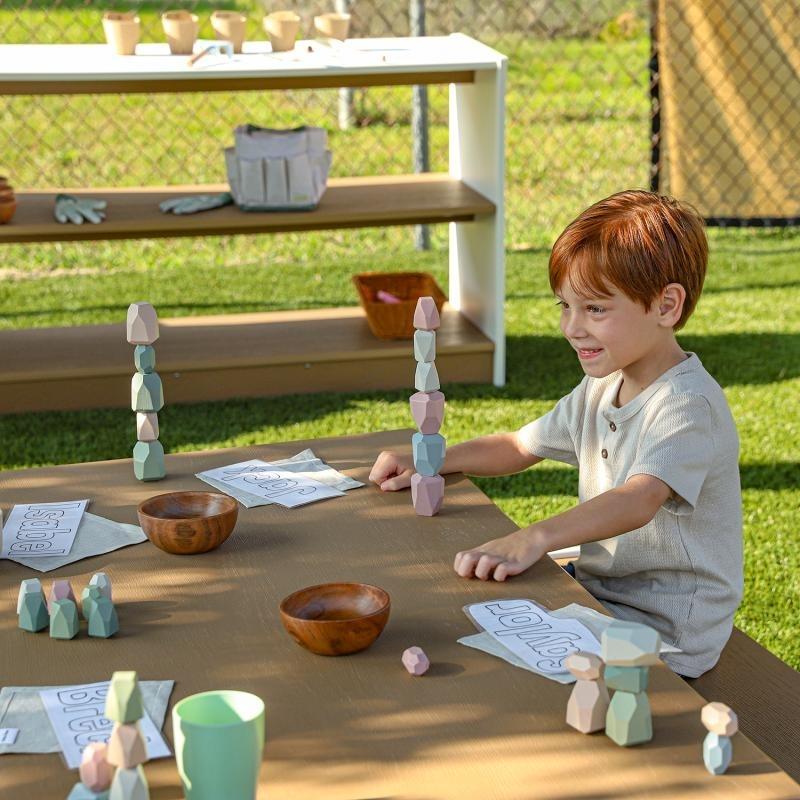 Boy actively engaged at the Whitney Brothers outdoorED outdoor classroom table, showing child-scaled 19.75-inch working height and sculpted leg clearance