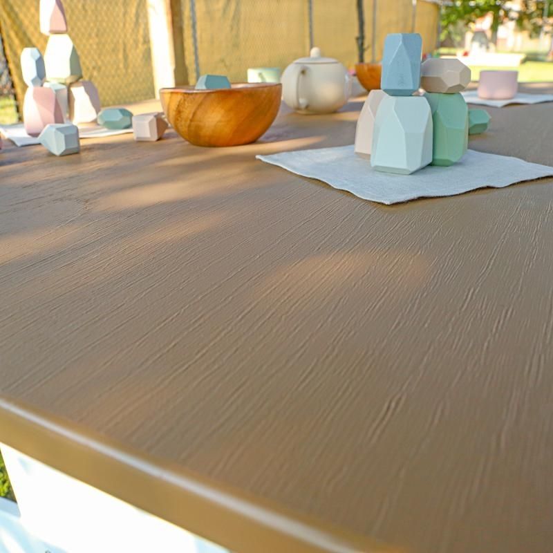 Close-up detail view of the Whitney Brothers outdoorED Table surface with learning materials, showing textured woodgrain maple finish and rounded safety edges