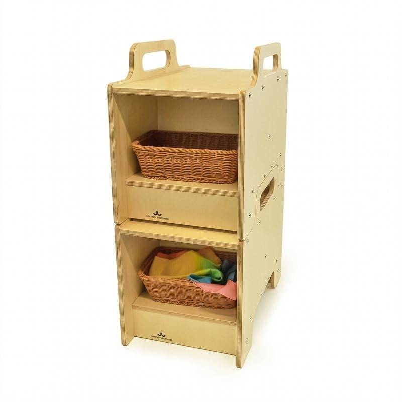 Two Whitney Brothers Stack-Able Seats stacked to form a two-sided storage cabinet with open compartments on both sides, each holding a wicker basket - showing the full flexible classroom storage and seating conversion in use