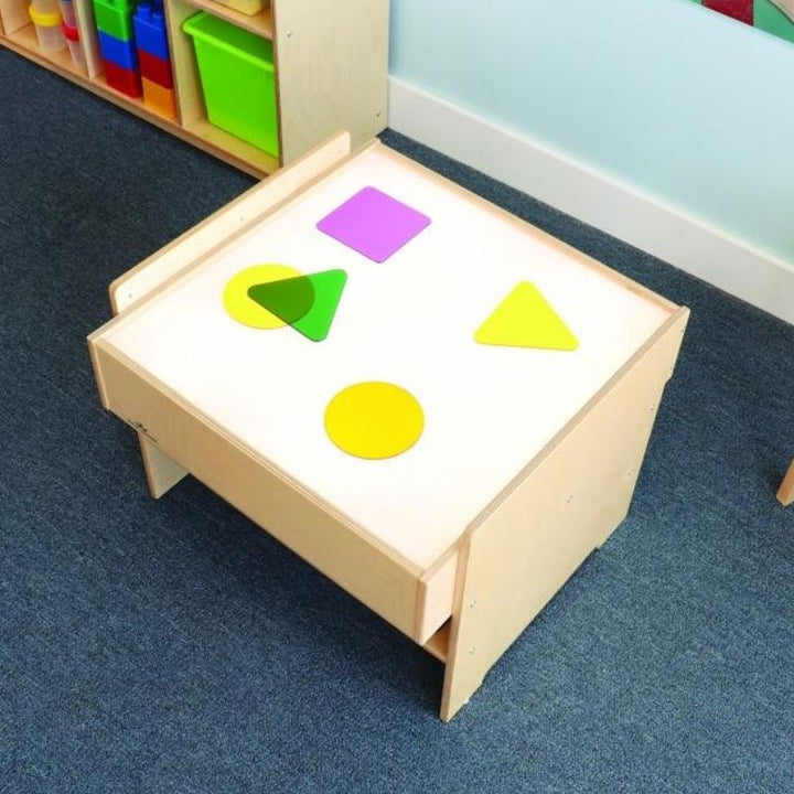 Top-down view of the Whitney Brothers Superbright LED Light Table showing an acrylic disc on the illuminated surface, demonstrating the SuperBright LED colour-reveal effect