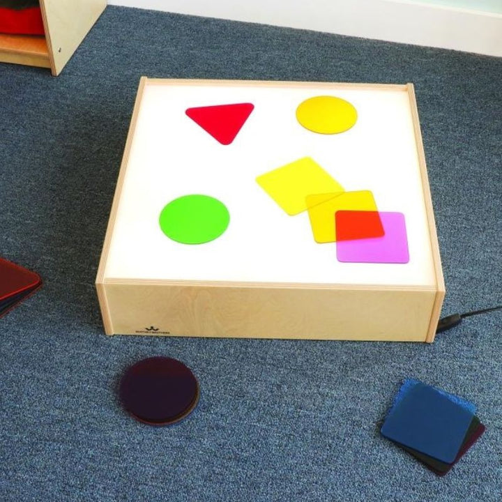 Top-down view of the Whitney Brothers Superbright LED Tabletop Light Box with coloured acrylic discs on the illuminated surface, showing the SuperBright LED colour-reveal effect
