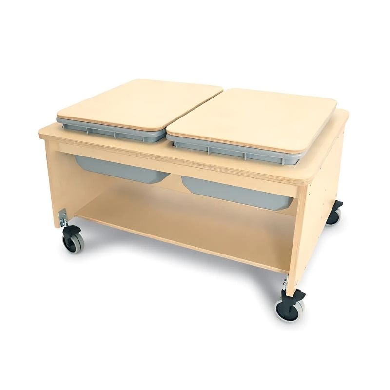 Portrait view of the Whitney Brothers Whitney Plus Two Tub Sand & Water Table with solid birch covers in place, showing the lockable casters and 1" thick HPL maple laminate table surface